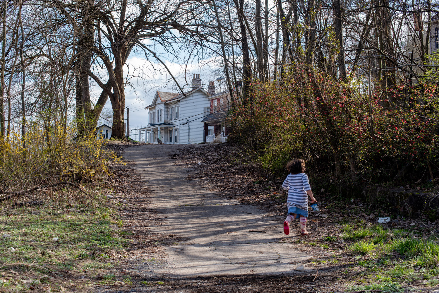 Photo of a child running along a former access road at the St. Johns Community Conservation project. Trees and flowering bushes surround the child as the site returns to a natural state.